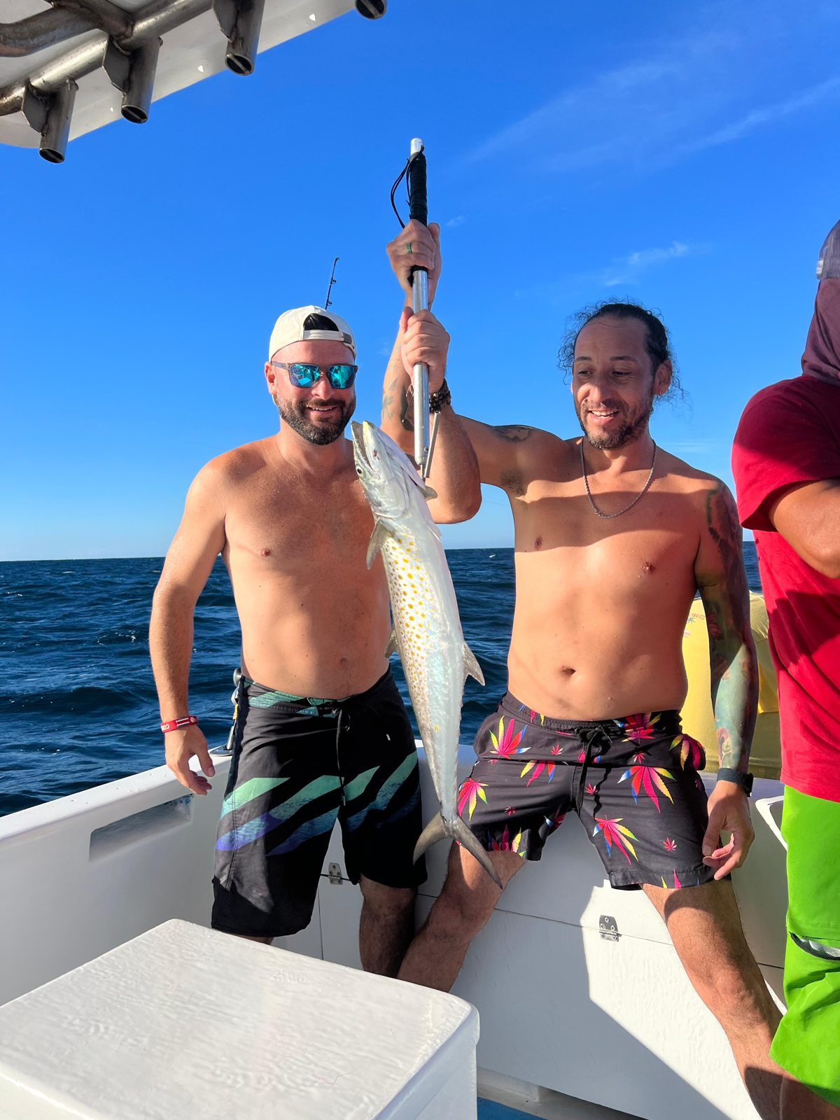Two guests proudly holding a fish after a boat trip